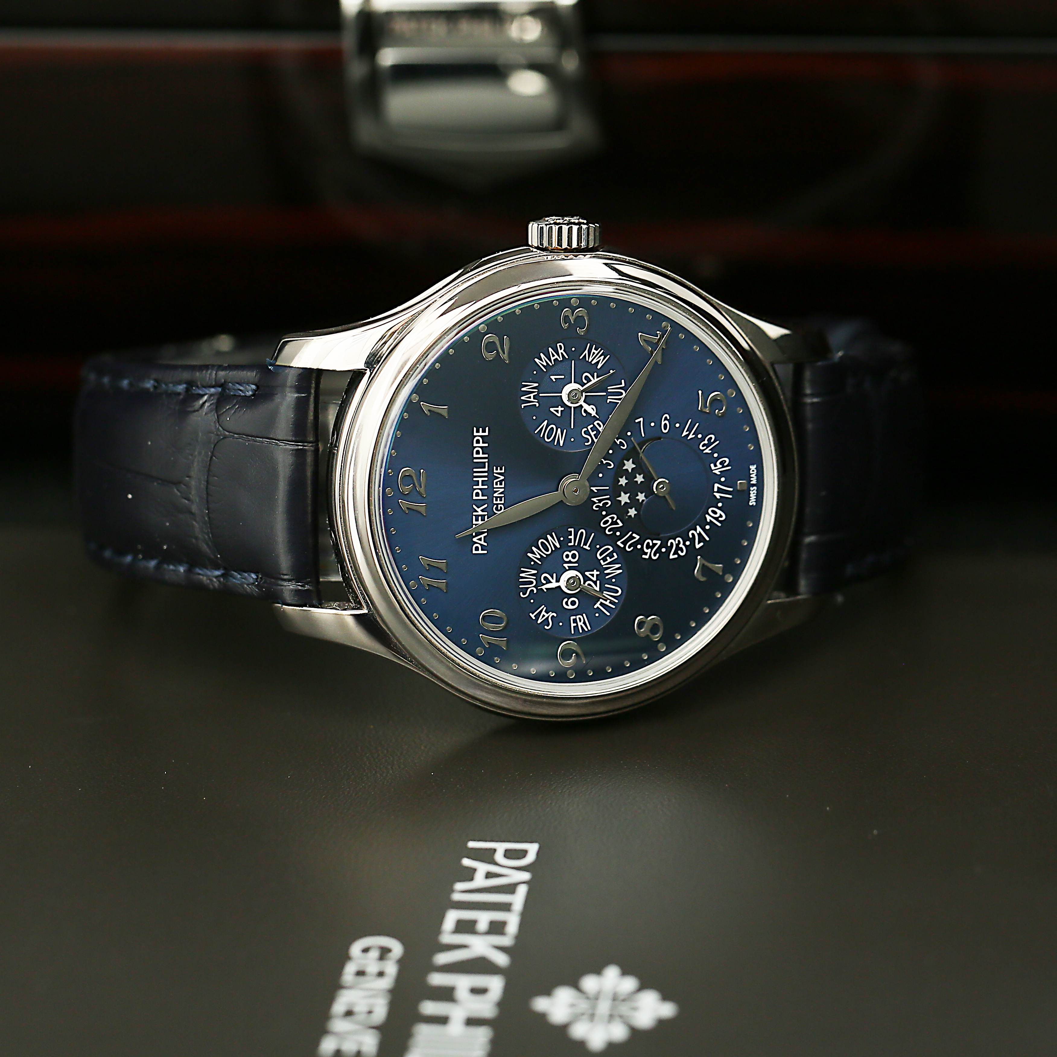 Patek Philippe 5327G with blue face and black leather strap on a dark background
