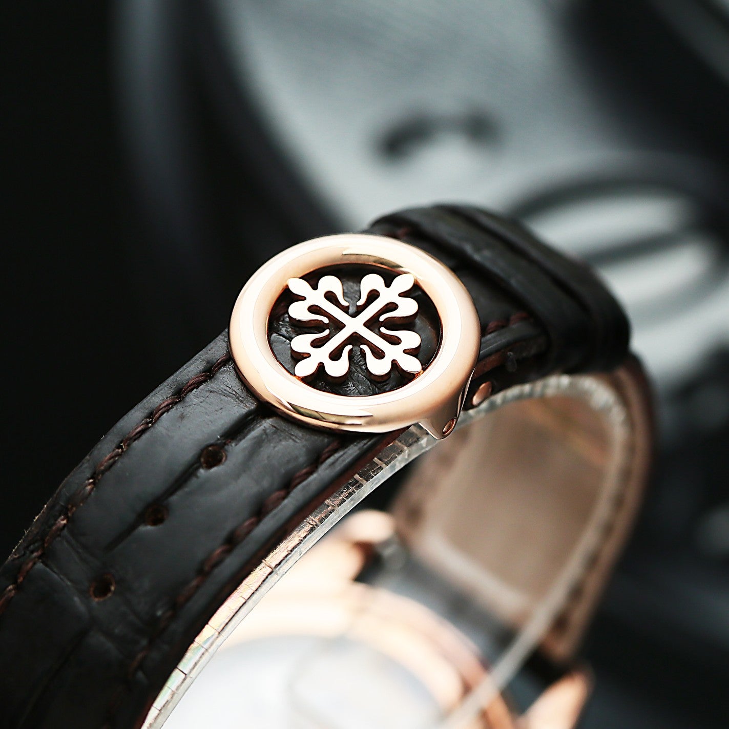 Close-up of a Patek Philippe 5146R with a decorative emblem on a black strap